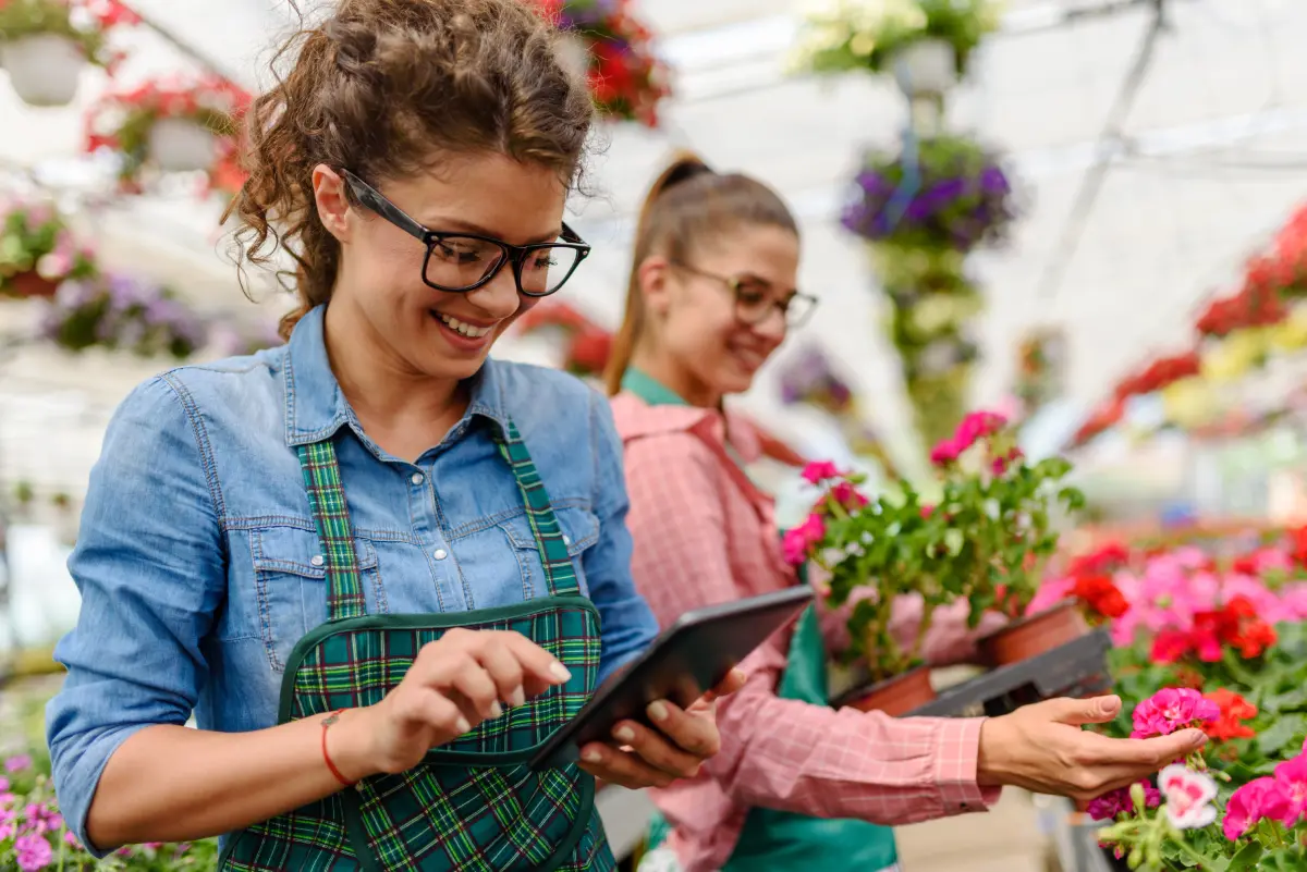 Young women working in beautiful garden center. Women enterpreneurs in team work.